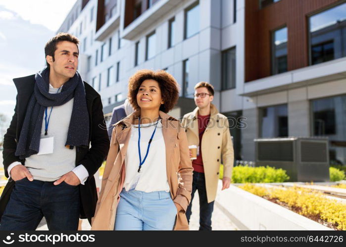 business, education and corporate concept - international group of people with coffee and conference badges on city street. people with coffee and conference badges in city