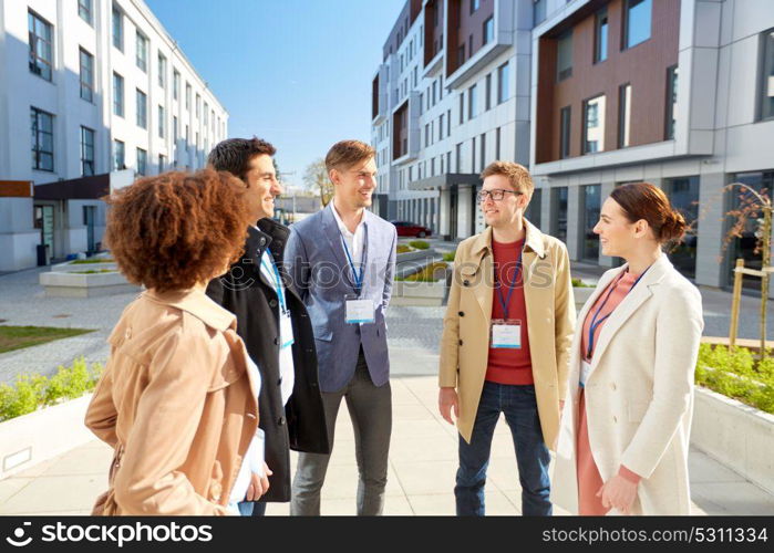 business, education and corporate concept - international group of people with conference badges on city street. business team with conference badges in city