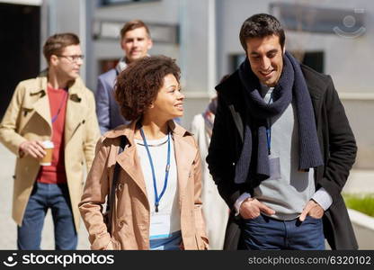 business, education and corporate concept - international group of people with conference badges on city street. business team with conference badges in city