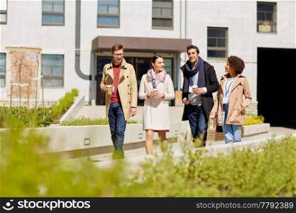 business, education and corporate people concept - happy international group of office workers with conference badges drinking coffee and talking outdoors. office workers with coffee on city street
