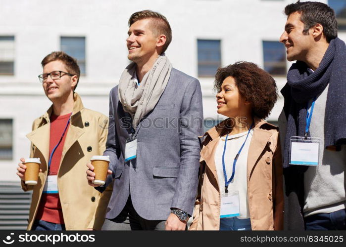 business, education and corporate people concept - office workers or friends with coffee cups talking on city street. office workers with coffee on city street