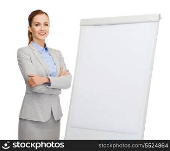 business, education and office concept - smiling businesswoman standing next to flip board