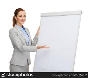 business, education and office concept - smiling businesswoman standing next to flip board and pointing hand