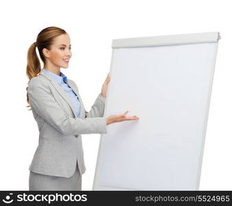 business, education and office concept - smiling businesswoman standing next to flip board and pointing hand