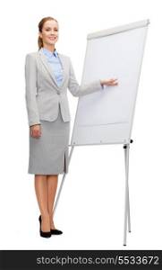 business, education and office concept - smiling businesswoman standing next to flip board and pointing hand