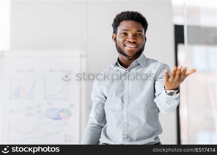 business, education and people concept - african american businessman with flip chart at office presentation. businessman with flip chart at office presentation. businessman with flip chart at office presentation