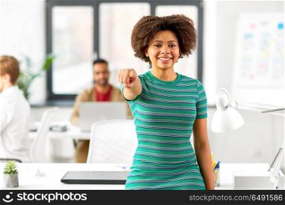 business, education and people concept - happy smiling african american woman pointing finger at you at office. smiling african woman pointing at you at office. smiling african woman pointing at you at office