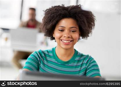 business, education and people concept - happy smiling young african american woman with laptop computer working at office. happy african woman with laptop computer at office. happy african woman with laptop computer at office