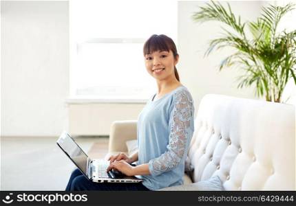 business, education and people concept - happy young asian woman with laptop computer working at office. happy asian woman with laptop computer at office