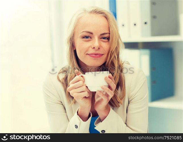 business, education and people concept - happy young businesswoman or student girl drinking coffee at office. happy businesswoman drinking coffee at office