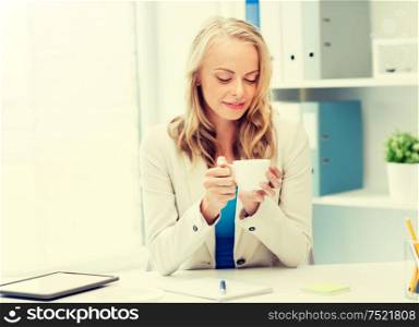 business, education and people concept - happy young businesswoman or student girl drinking coffee at office. happy businesswoman drinking coffee at office