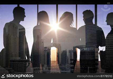 business, education and people concept - people silhouettes over double exposure office and city background