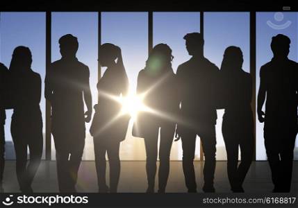 business, education and people concept - people silhouettes over office background