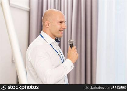 business, education and people concept - smiling businessman talking to microphone at conference. businessman with microphone at business conference