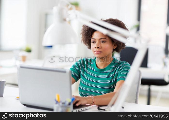 business, education and people concept - young african american woman with laptop computer working at office. african woman with laptop computer at office