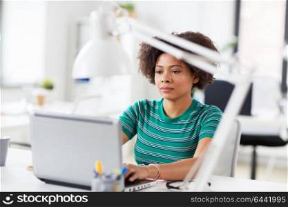 business, education and people concept - young african american woman with laptop computer working at office. african woman with laptop computer at office