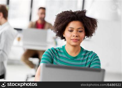 business, education and people concept - young african american woman with laptop computer working at office. african woman with laptop computer at office. african woman with laptop computer at office