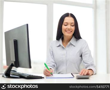 business, education and technology concept - happy businesswoman with computer, notebook and calculator in office