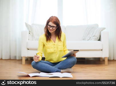 business, education and technology concept - smiling female student in eyeglasses with notebooks and tablet pc computer at home