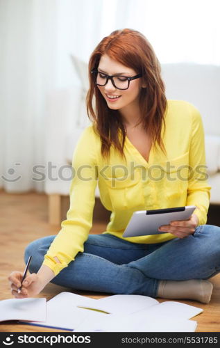 business, education and technology concept - smiling female student in eyeglasses with notebooks and tablet pc computer at home