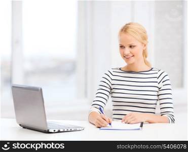 business, education and technology concept - smiling student with laptop computer and notebook in college