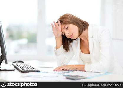 business, education and technology concept - tired businesswoman with computer, papers and calculator at work