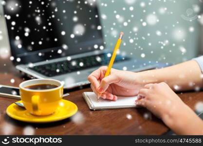 business, education, freelance, people and inspiration concept - close up of woman writing to notebook with pencil over snow