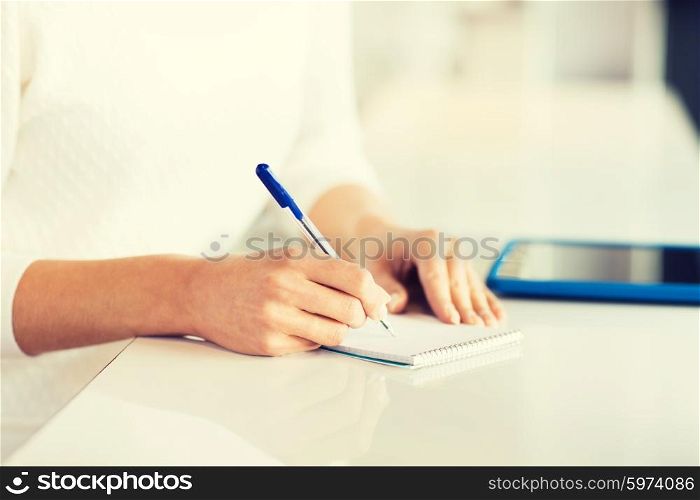 business, education, people and lifestyle concept - close up of woman hands with pen writing to notepad