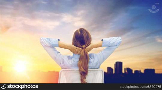 business, education, people and office concept - businesswoman sitting on chair from back over city background. businesswoman sitting on chair from back