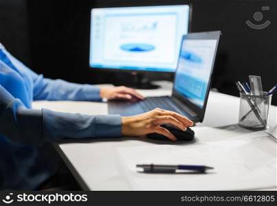 business, education, people and technology concept - close up of female hand with laptop and computer mouse on table. close up of female hand using computer mouse