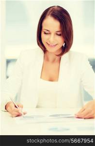 business, education, people concept - businesswoman or student working with graphs in office