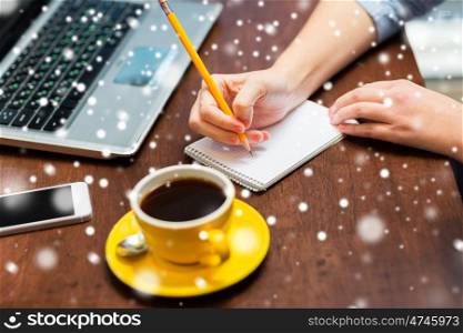 business, education, people, technology and lifestyle concept - woman writing to notebook with pencil over snow