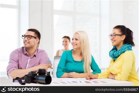 business, education, photography, office and startup concept - smiling creative team with photocamera listening to lecture in office