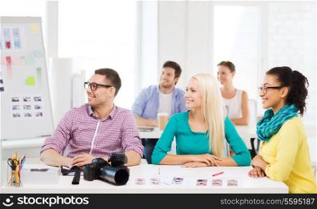 business, education, photography, office and startup concept - smiling creative team with photocamera listening to lecture in office