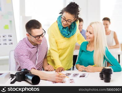 business, education, photography, office and startup concept - smiling creative team with printed photos working in office