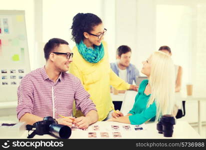 business, education, photography, office and startup concept - smiling creative team with printed photos working in office