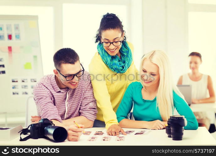 business, education, photography, office and startup concept - smiling creative team with printed photos working in office