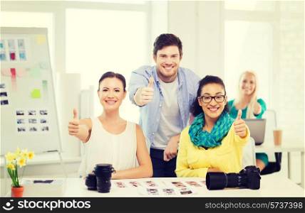 business, education, photography, office and startup concept - smiling creative team with photocamera in office showing thumbs up