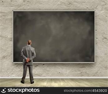 Business education. Rear view of businessman looking at chalkboard