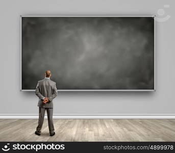 Business education. Rear view of businessman looking at chalkboard