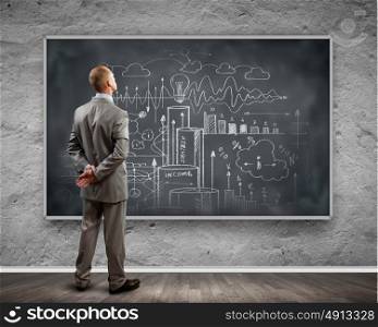 Business education. Rear view of businessman looking at chalkboard