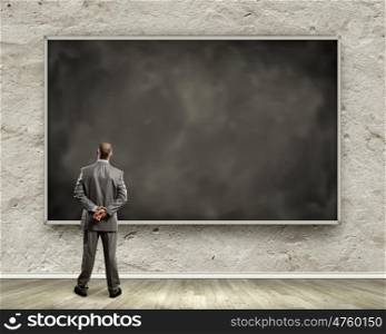 Business education. Rear view of businessman looking at chalkboard. Place for text