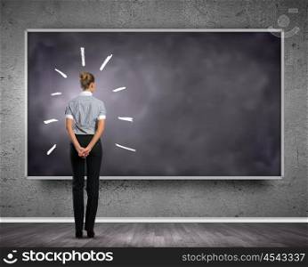 Business education. Rear view of businesswoman looking at chalkboard