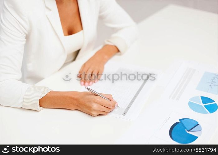 business, education, school, documents, people concept - businesswoman or student working with graphs in office
