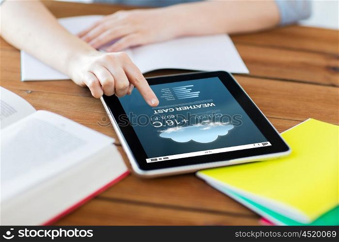 business, education, technology and internet concept - close up of student woman with weather forecast application on tablet pc computer and notebook at home