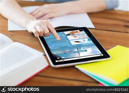business, education, technology and internet concept - close up of student woman with internet news application on tablet pc computer screen and notebook at home