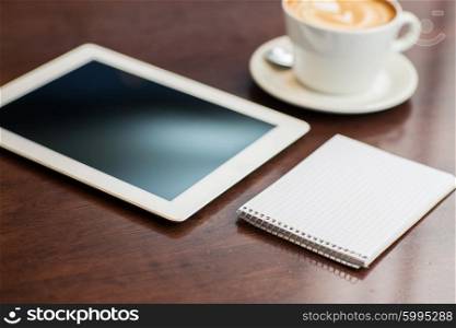 business, education, technology and object concept - close up of notebook with tablet pc computer and coffee on table