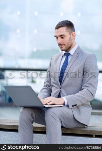 business, education, technology and people concept - businessman working with laptop computer on city street