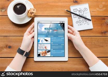 business, education, technology and people concept - close up of woman with internet news application on tablet pc computer screen, notebook and coffee on wooden table