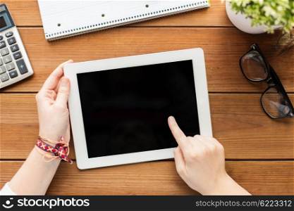 business, education, technology and people concept - close up of woman with blank tablet pc computer screen, calculator and eyeglasses on wooden table